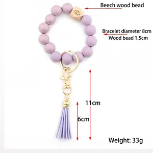 Purple beaded bracelet keychain with wooden eye bead, gold ring and leather tassel charm