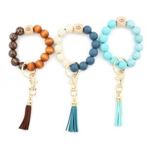 Detail of printed wood bead bracelet keychains with leather tassels and gold clasps