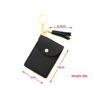 Detail of black pebbled leather card holder with gold snap button, keychain, and tassel
