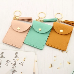 Leather tassel keychain wallet set in pink, green, and yellow on white wood surface