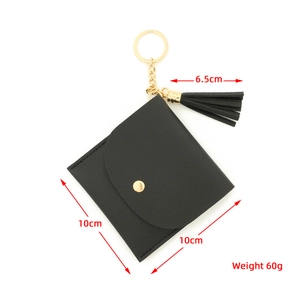 Detail view of small black PU leather wallet with gold snap closure and tassel