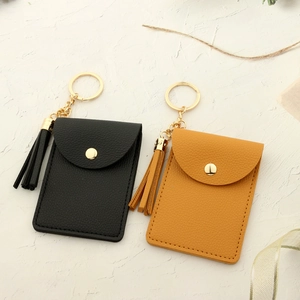 Detail view of black and yellow leather card holder keychains with tassel and gold snap