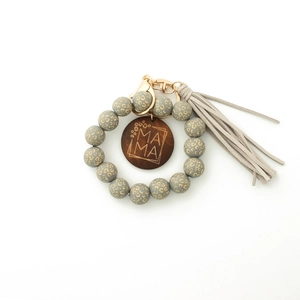 Détail d'un porte-clés à perles léopard avec disque en bois Mama et pompon élégant