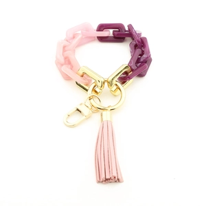 Détail du porte-clés en acrylique rose et violet avec anneau doré et gland souple