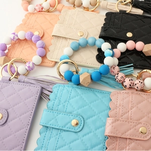 Close-up of quilted leather card holders with colorful silicone bead wristlet and tassel