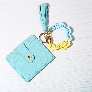 Detail of light blue quilted leather card holder with tassel and colorful chain link