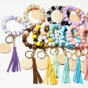 Detail of silicone bead wristlet keychains with leopard print, tassels, and wood tags