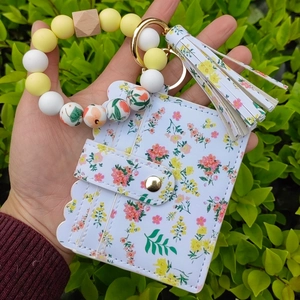 Close-up of floral wallet and silicone bead keychain wristlet held outdoors