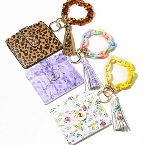 Close-up of leather card holders with floral, leopard patterns and resin chain handles