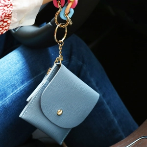 Detail view of light blue leather card wallet with colorful acrylic keychain and gold clasp
