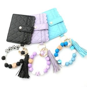 Close-up of quilted leather wallets with silicone bead wristlets in black, purple, and blue