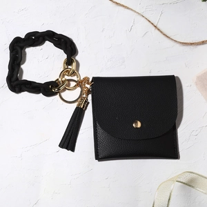 Close-up of black pebble leather wallet with chunky matte chain and tassel on stone base