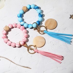 Close-up of marble silicone bead keychains with wooden accents and suede tassels on stone