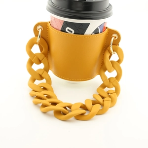 Ginger yellow leather coffee cup sleeve with thick plastic chain handle on white background