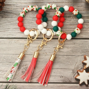 Detail of Christmas silicone bead bracelet with Santa prints, tassels and gold keychain