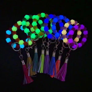 Luminous silicone bead keychain with colorful tassels and glowing beads on black background
