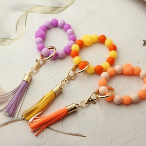 Detailed macro view of colorful silicone bead keychains with leather tassels and gold clasps