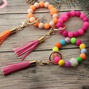 Detailed top view of luminous silicone bead keychains with tassels on a wooden background