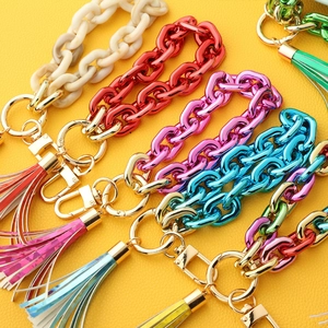 Colorful acrylic chain keychain bracelets with leather tassels on yellow background