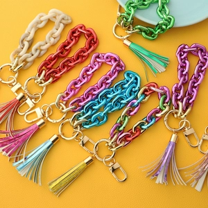 Close-up of colorful acrylic chain keychains with iridescent tassels on yellow leather