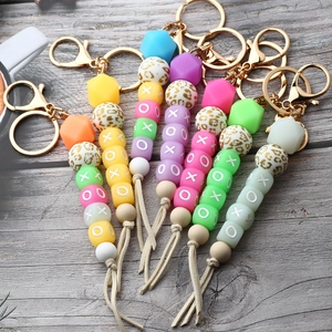 Detail of colorful XOXO silicone bead keychains with leopard print and suede tassels