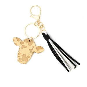 Detail of wooden cow head keychain with black and white tassels and gold hardware