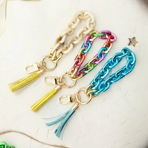 Macro detail of acrylic keychain wristbands with colorful tassels and gold lobster clasps