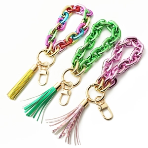 Close-up of colorful acrylic chain bracelets with metallic tassels and gold lobster clasps