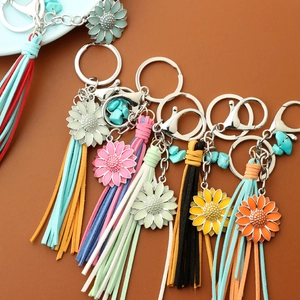 Detail of colorful tassel keychains with daisy charm and turquoise on leather texture