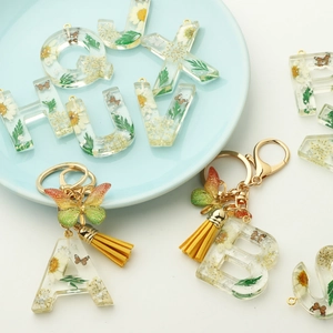 Resin initial keychain with real dried flowers, yellow tassels, and butterfly charms