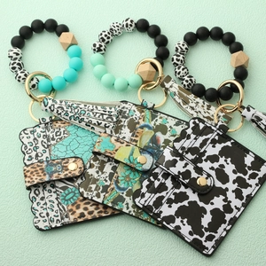 Detail of three western-style silicone bead wristlets with cow and floral print card holders