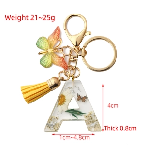 Floral resin letter A keychain with yellow butterfly and gold tassel on white background