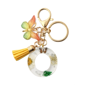 Resin letter O keychain with dried daisy, yellow tassel and green butterfly charm