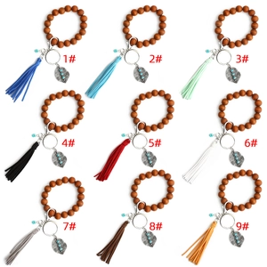 Detail view of nine colorful bohemian beaded wood keychains with leaf charms and tassels