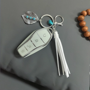 Close-up of bohemian key case with silver leaf pendant and blue stone detail