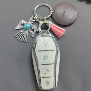Detail of white car key cover with eagle pendant, turquoise accent and pink leather tassel