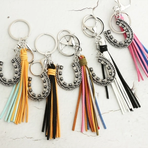 Bohemian silver horseshoe keychains with colorful faux suede tassels on marble surface
