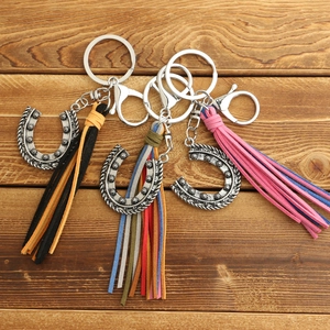 Set of Bohemian horseshoe keychains with colorful suede tassels on wood background