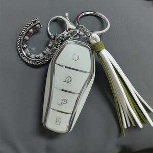 White car key cover with silver metal trim, retro horseshoe charm and bicolor tassel