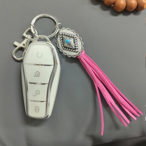 Detailed view of white car key cover with vintage turquoise pendant and pink leather tassel
