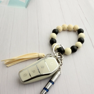 Dettaglio del bracciale portachiavi a perline con stampa leopardata, nappa in pelle e chiave