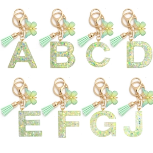 Green resin alphabet keychain set with butterfly charms and sparkles on white background