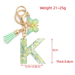 Letter K resin keychain with green butterfly charm and holographic glitter accents