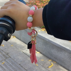 Detail of pink and white silicone bead wristlet keychain with gold ring and tassel