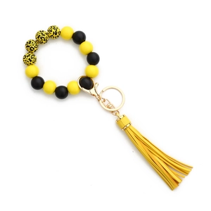 Détail du porte-clés en silicone jaune avec perles léopard et breloque à pompon en cuir