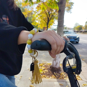 Yellow and white silicone bead wristlet keychain with leather tassel on bicycle handlebar