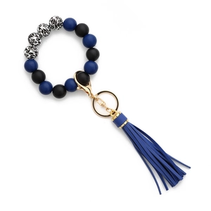 Détail du porte-clés perlé avec motifs léopard et pompon en cuir bleu pour le poignet