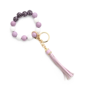Détail d'un porte-clés bracelet en perles de silicone léopard violettes avec pompon en cuir