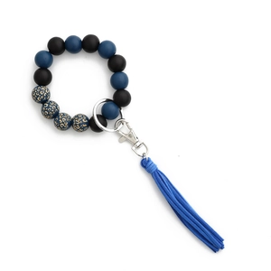 Dettaglio di perle leopardate e nappa in pelle scamosciata blu su un portachiavi da polso