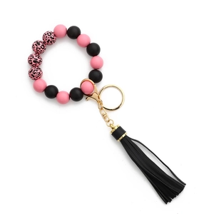 Détail du bracelet porte-clés à perles léopard roses et pompon en cuir noir élégant